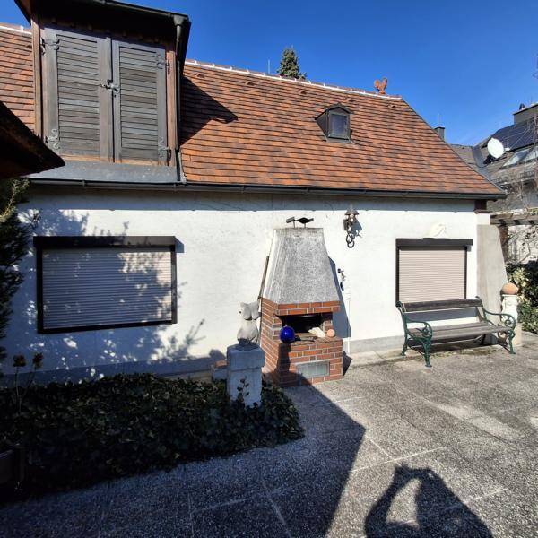Sonnige Terrasse mit Außenkamin und Sitzbank, ideal für gemütliche Stunden im Freien.