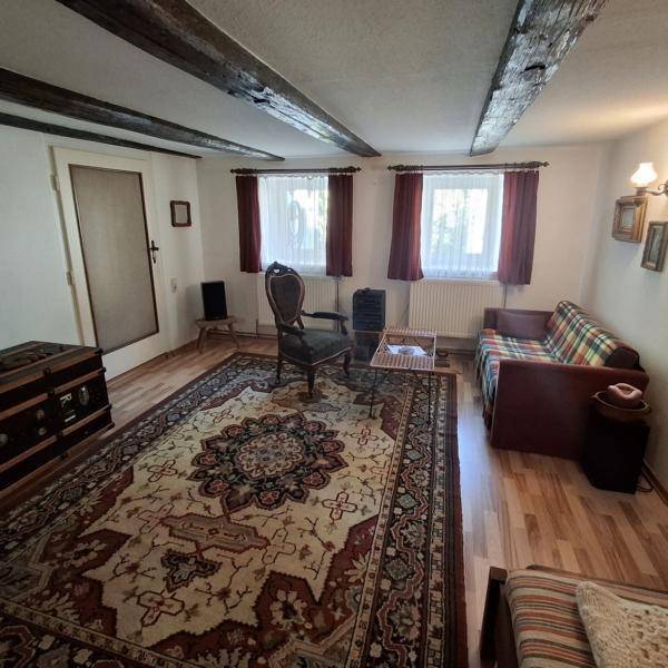 Geräumiges Wohnzimmer mit Holzbalken, Parkettboden und einem großen Teppich.