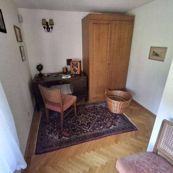 Arbeitsbereich mit Holzboden, Schreibtisch, Holzschrank und einem Fenster.