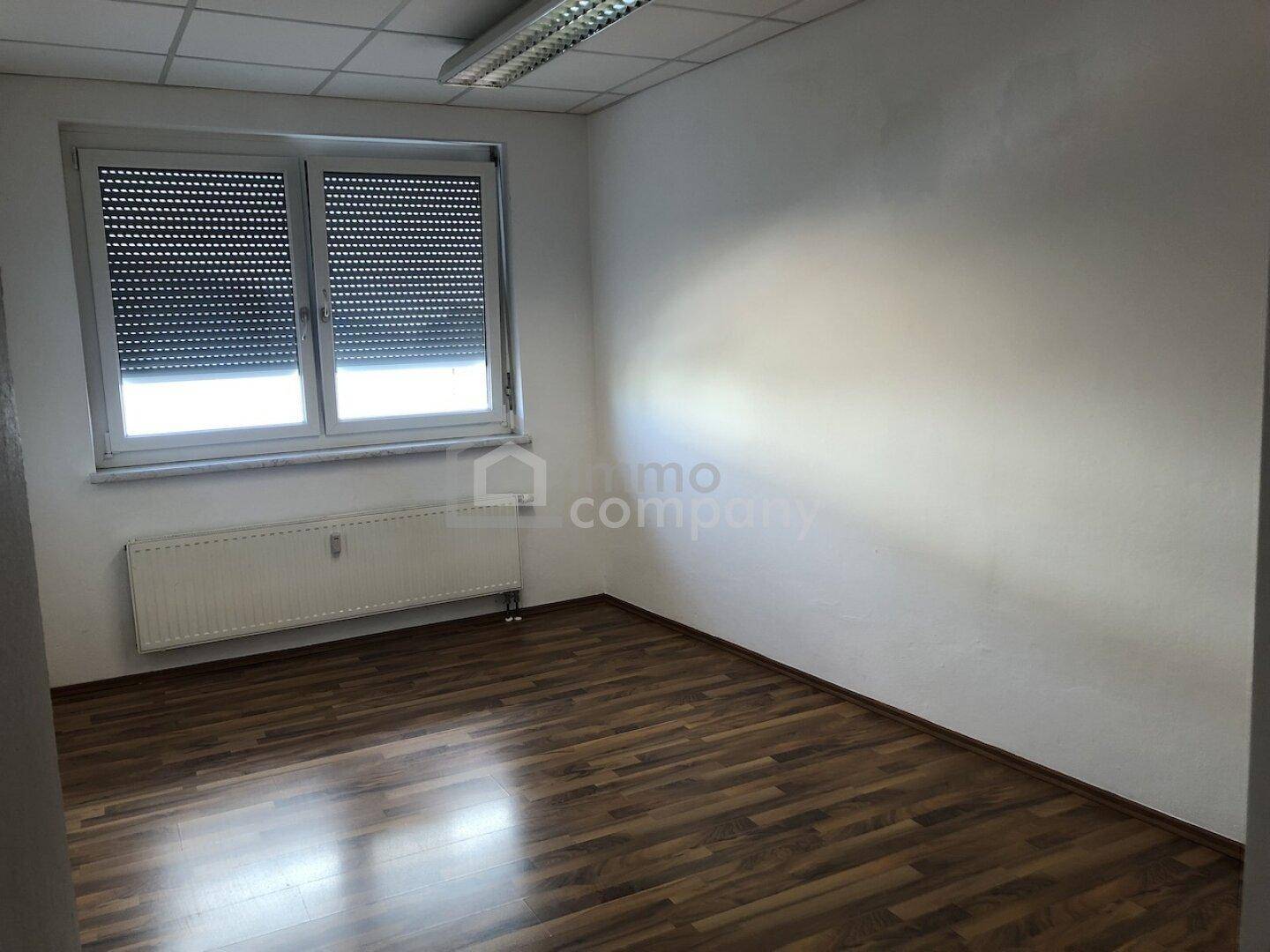 Leerer Raum mit Laminatboden und Fenster mit Rollläden, geeignet als Büro oder kleines Zimmer.