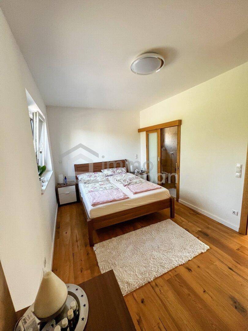 Gemütliches Schlafzimmer mit Holzboden, Doppelbett und Zugang zu einem angrenzenden Bad.