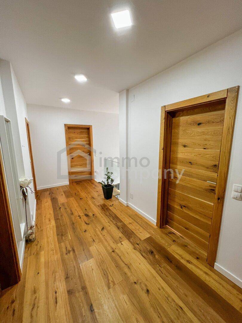 Langer Flur mit Holzboden und mehreren Holztüren, der verschiedene Wohnbereiche verbindet.