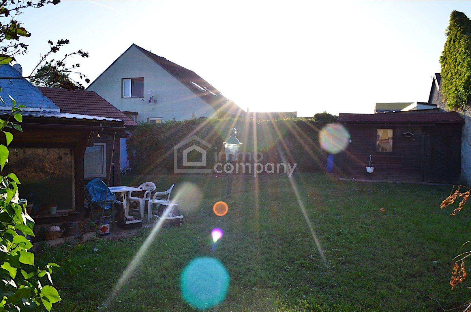 Weitläufiger Gartenbereich mit Rasen, Sitzgelegenheiten und viel Sonnenlicht am Nachmittag.