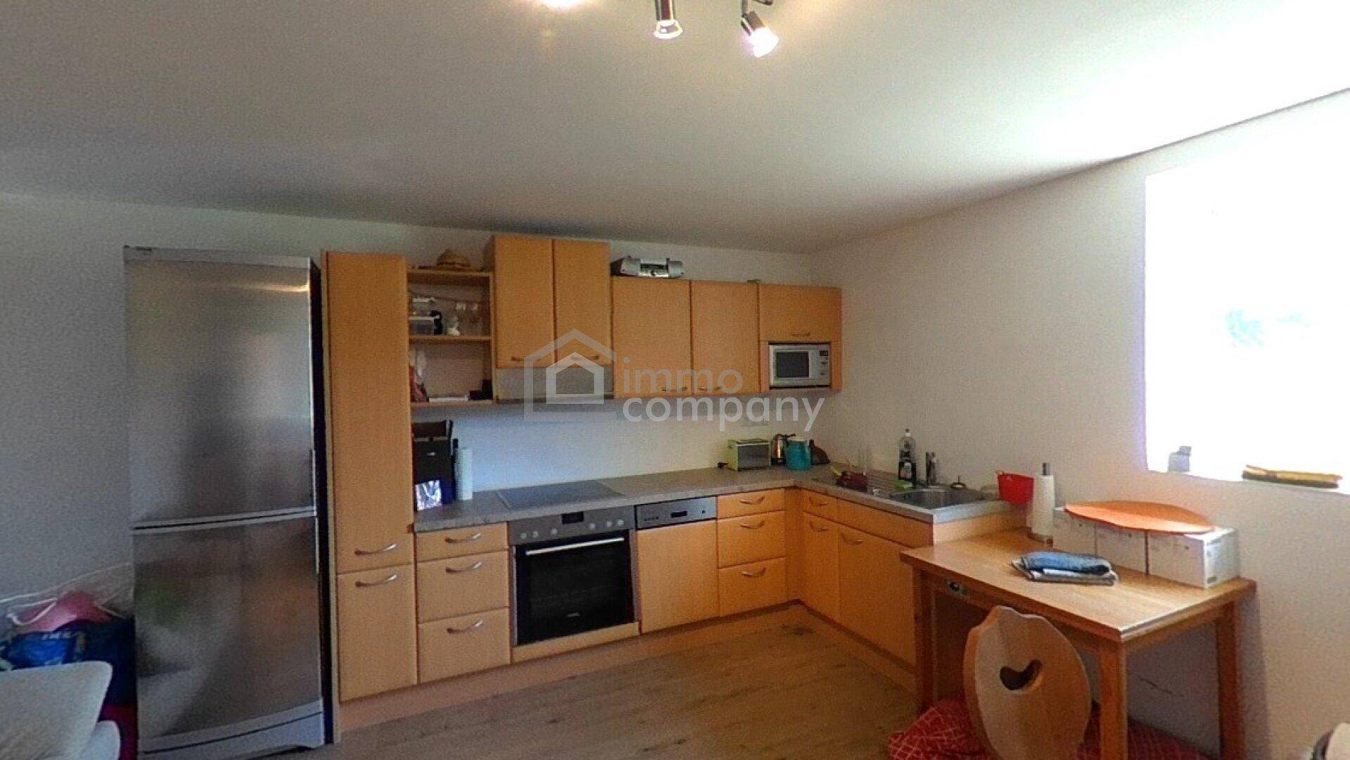 Funktionale Küche mit Holzschränken, modernen Geräten und einem großen Kühlschrank.