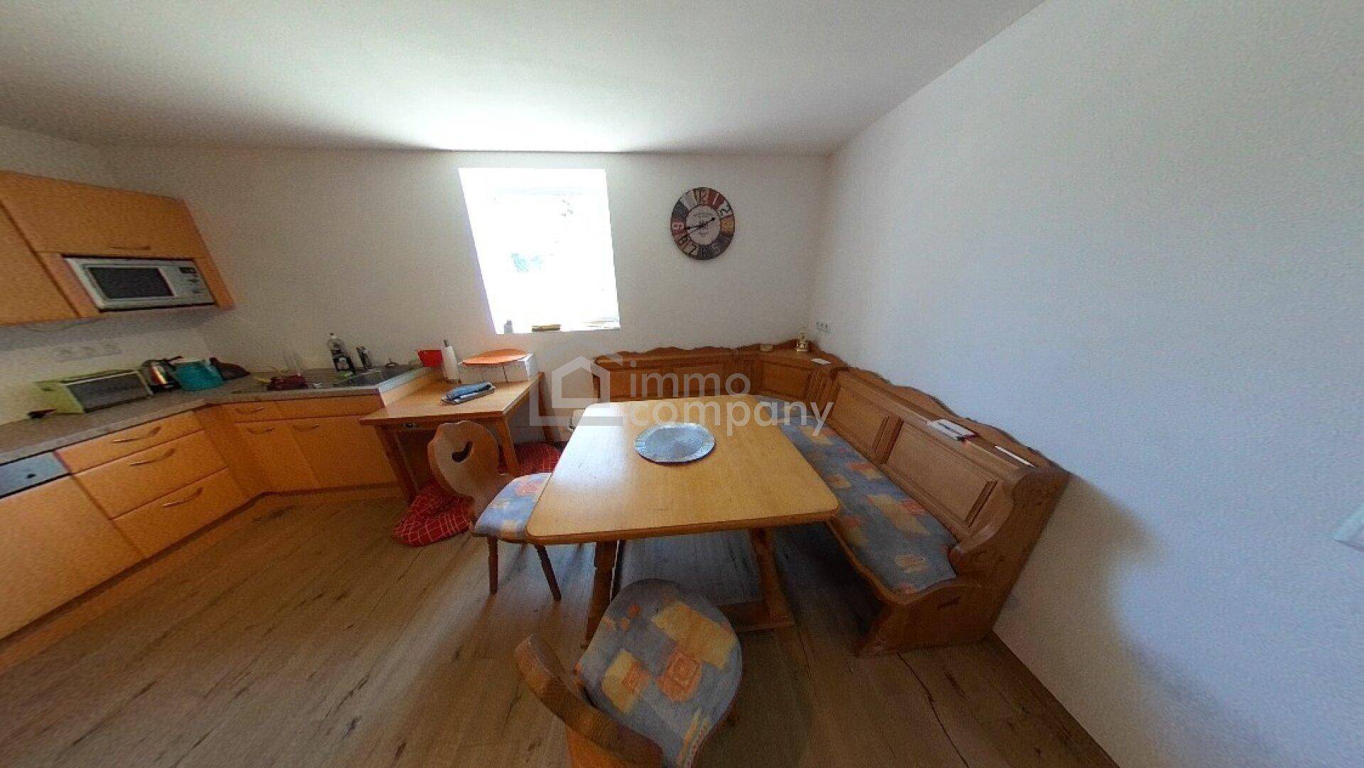 Traditionelle Wohnküche mit Holzeinrichtung, integrierter Essecke und einem Fenster für Tageslicht.