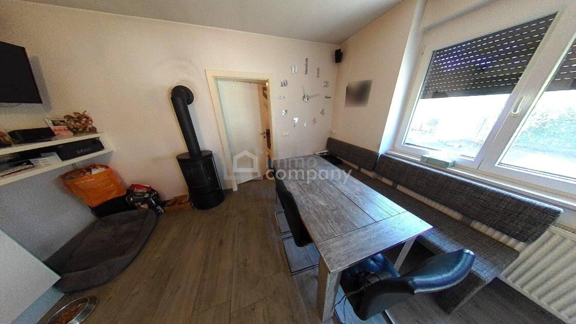 Gemütlicher Essbereich mit Holztisch, Sitzbank und einem traditionellen Holzofen.