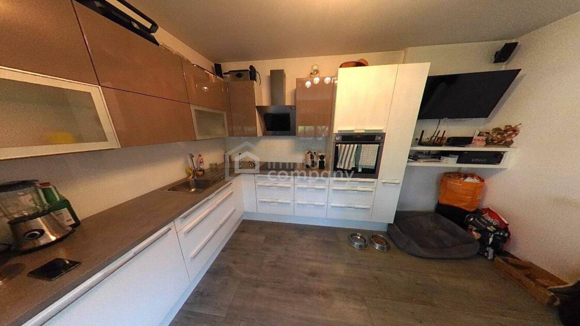 Moderne Küche mit Hochglanzschränken, Dunstabzugshaube und integrierten Elektrogeräten.