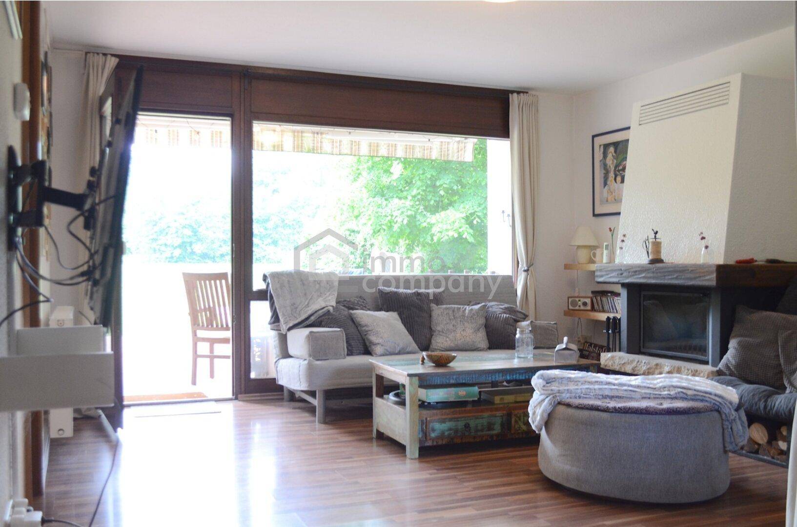 Gemütliches Wohnzimmer mit Kamin, Holzboden und Zugang zu einer Außenterrasse.