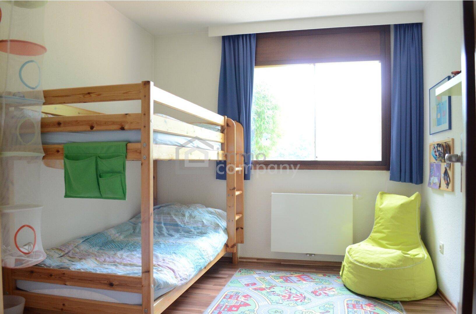 Kinderzimmer mit Etagenbett, Holzboden und einem großen Fenster für viel Tageslicht.