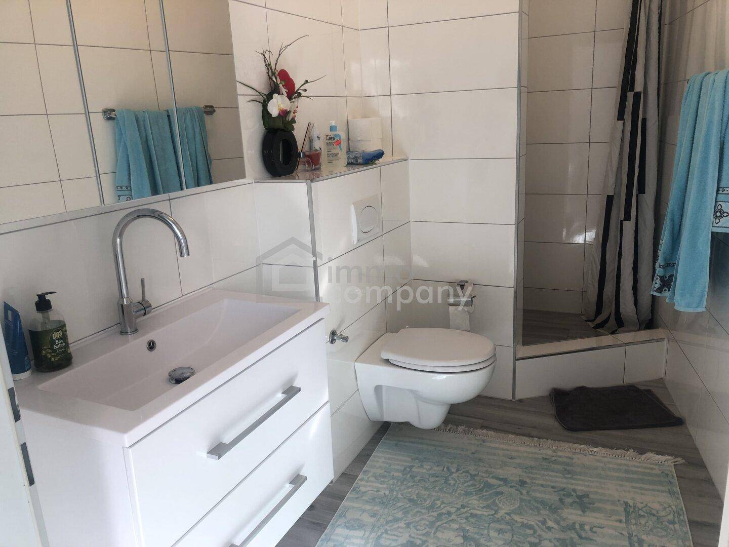 Modernes Badezimmer mit Duschbereich, wandhängendem WC und Waschbecken.