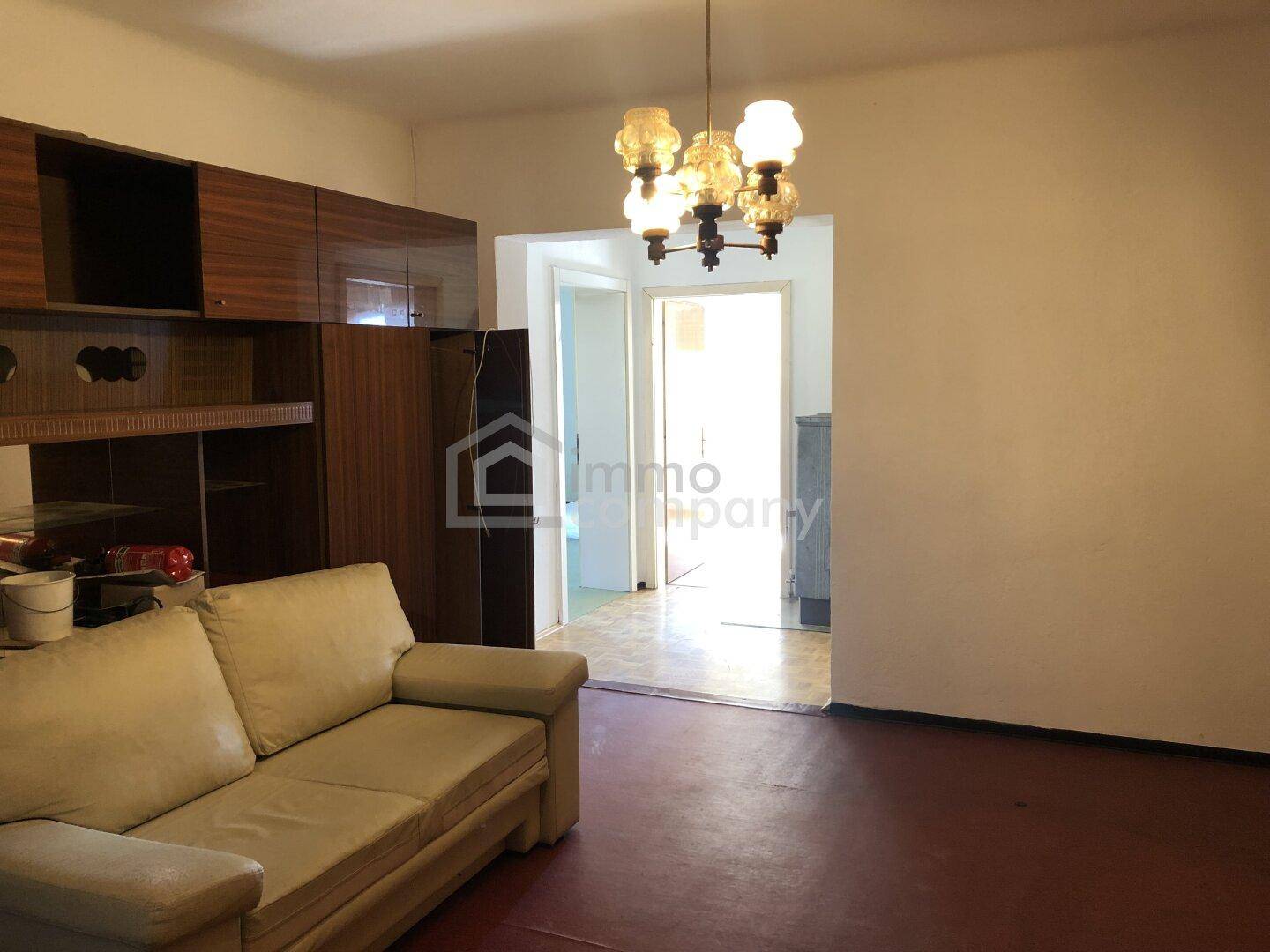 Wohnzimmer mit Sofa, Holzregal und Durchgang zu weiteren Räumen.