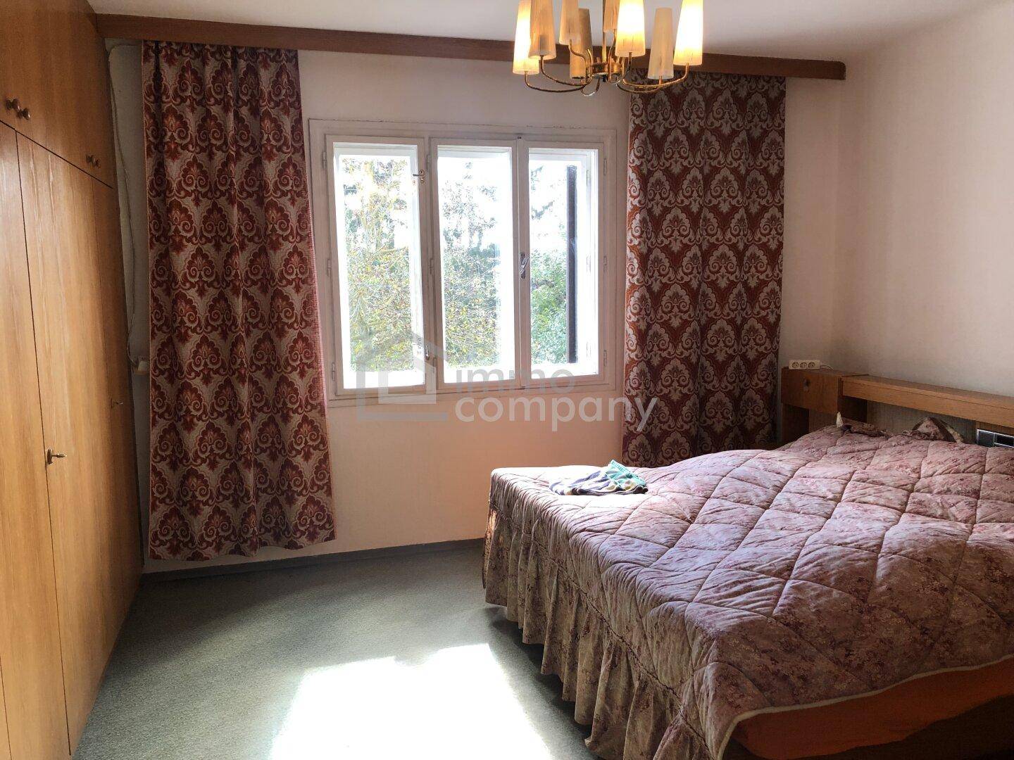 Schlafzimmer mit Doppelbett, Holzschrank und Fenster mit Blick ins Grüne.