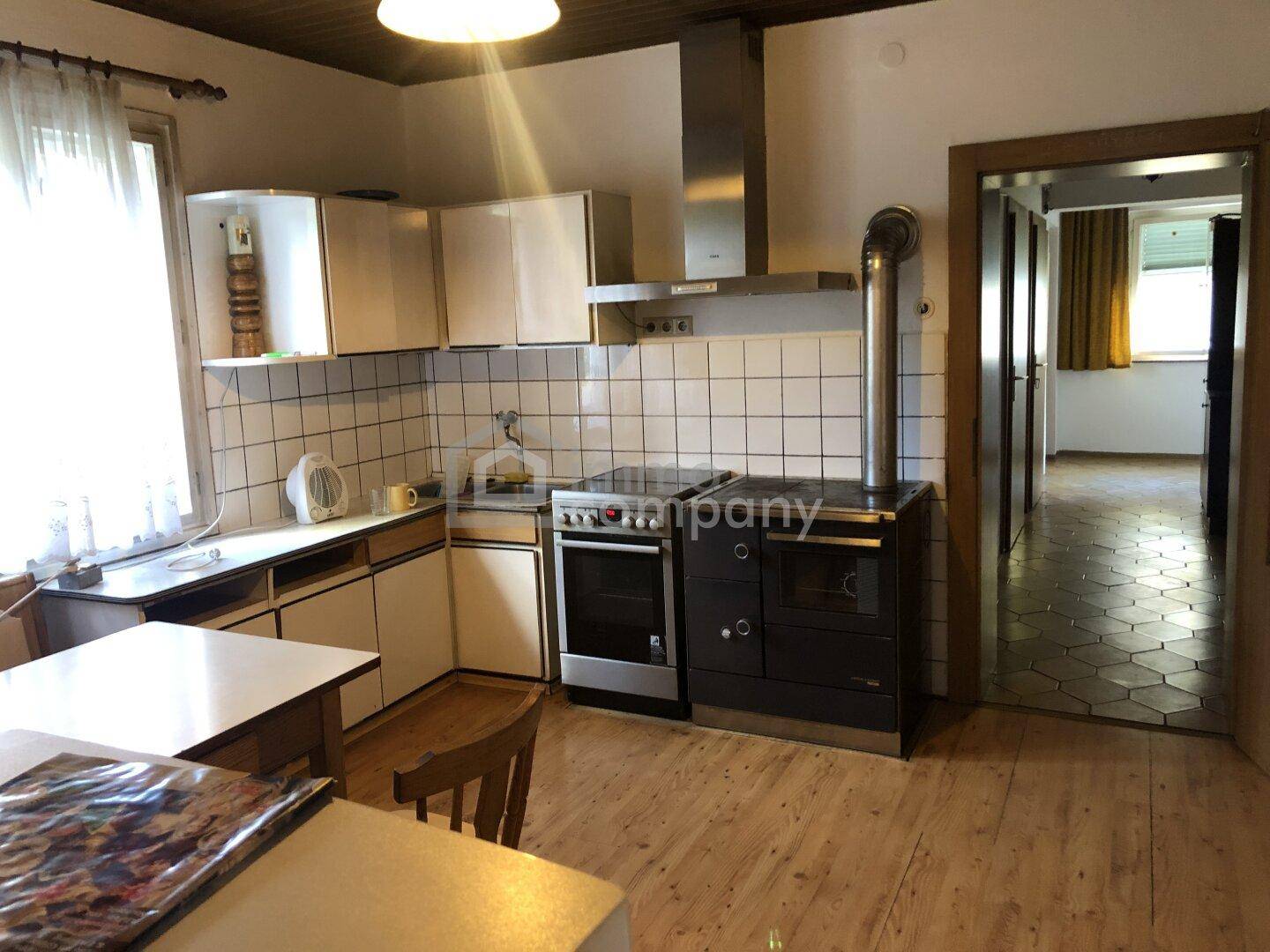 Küche mit traditionellem Holzofen, Einbauschränken und Holzboden.