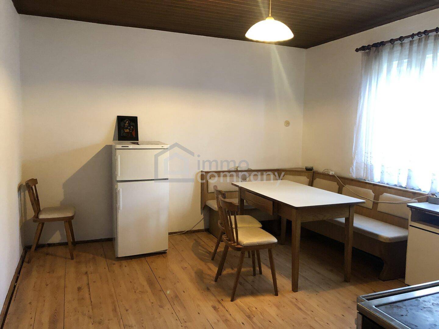 Essbereich mit Holztisch, Eckbank und Kühlschrank, ideal für Familienmahlzeiten.