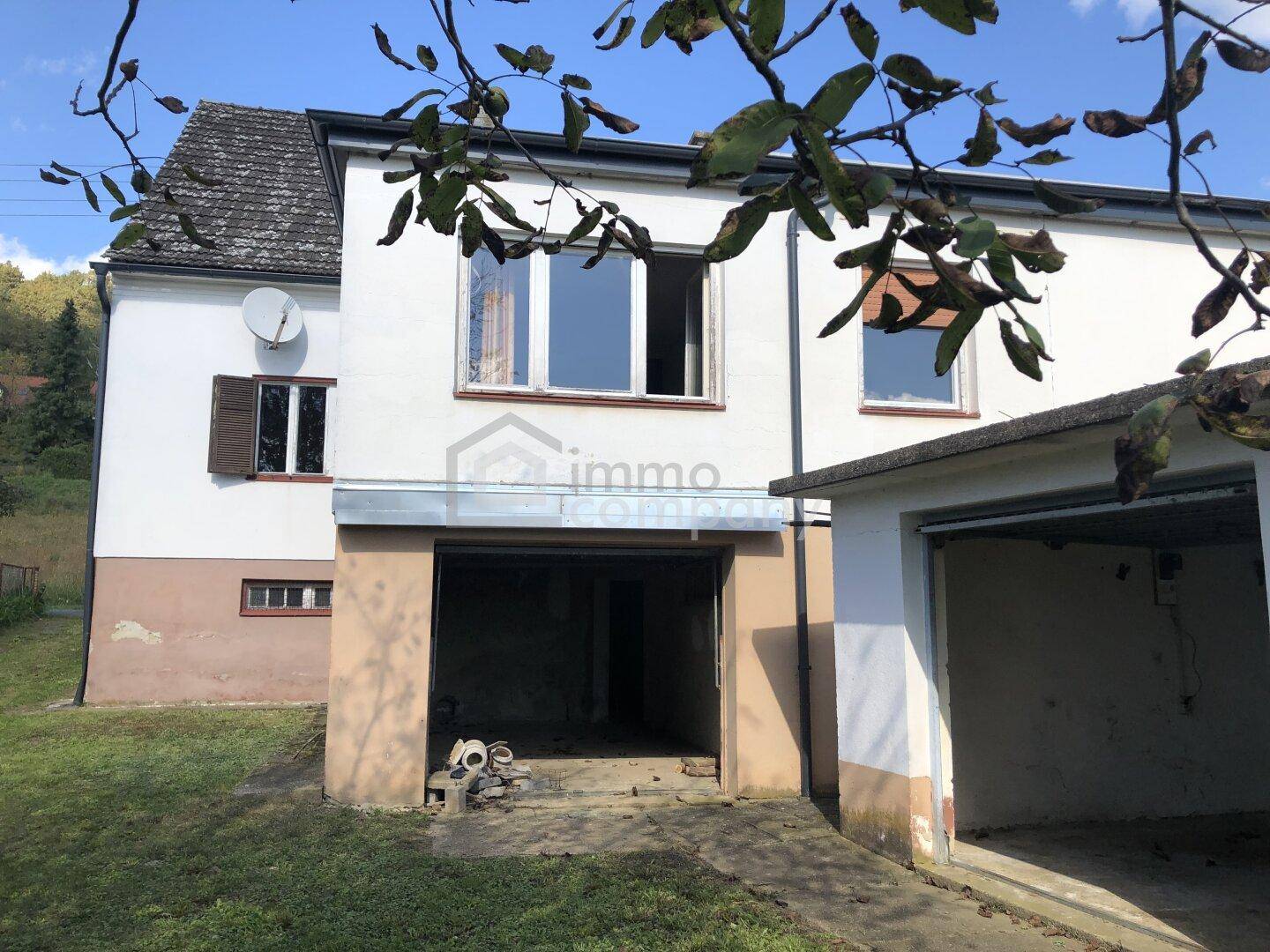 Rückseite des Hauses mit integrierter Garage und Blick auf die umliegende Natur.