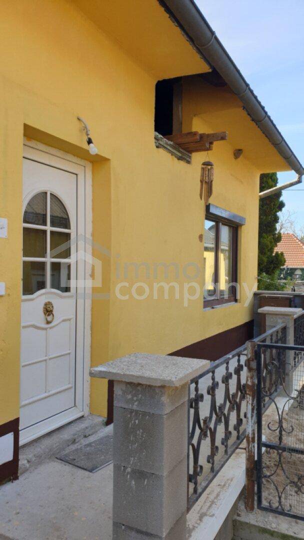 Eingangsbereich des Hauses mit weißer Tür, Fenster und einem kleinen Geländer.