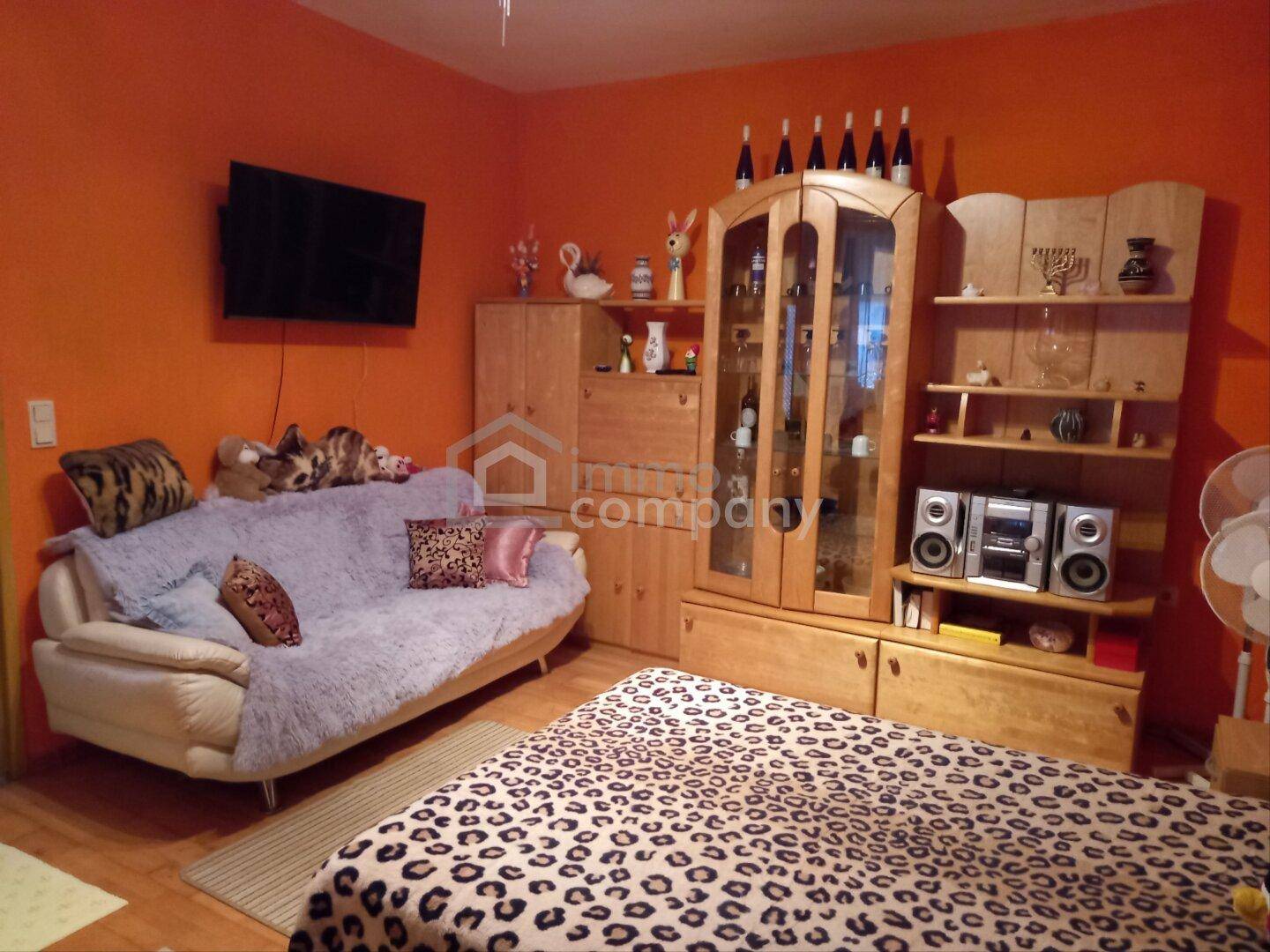 Schlafzimmer mit orangefarbenen Wänden, Doppelbett und Holzschränken.