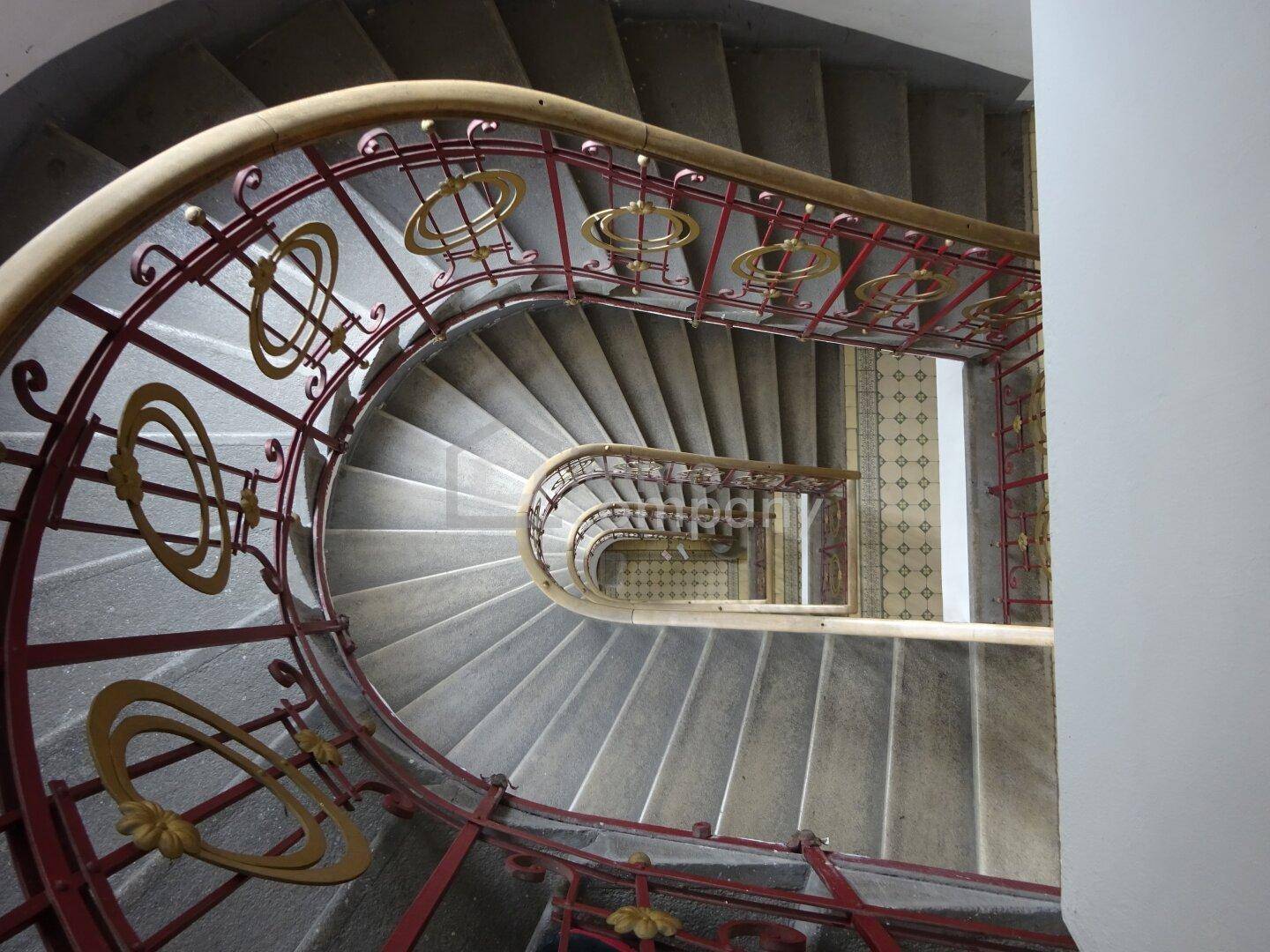 Elegantes Wendeltreppenhaus mit kunstvollem schmiedeeisernem Geländer und Steinstufen.