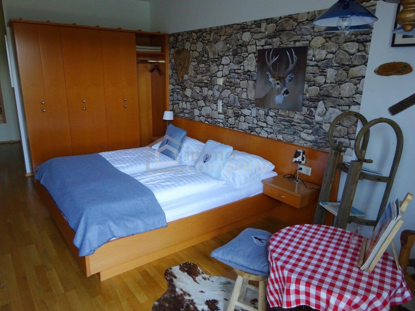 Rustikales Schlafzimmer mit Steinwand-Optik, Holzboden und großem Kleiderschrank.