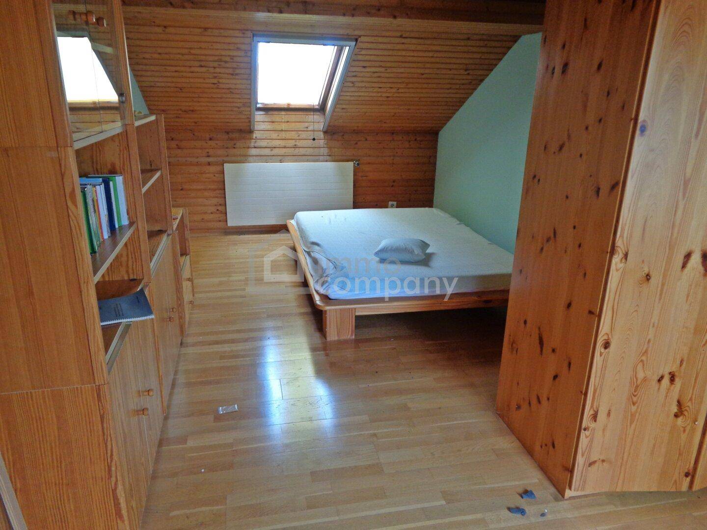 Gemütliches Schlafzimmer im Dachgeschoss mit Holzverkleidung und Dachfenster.
