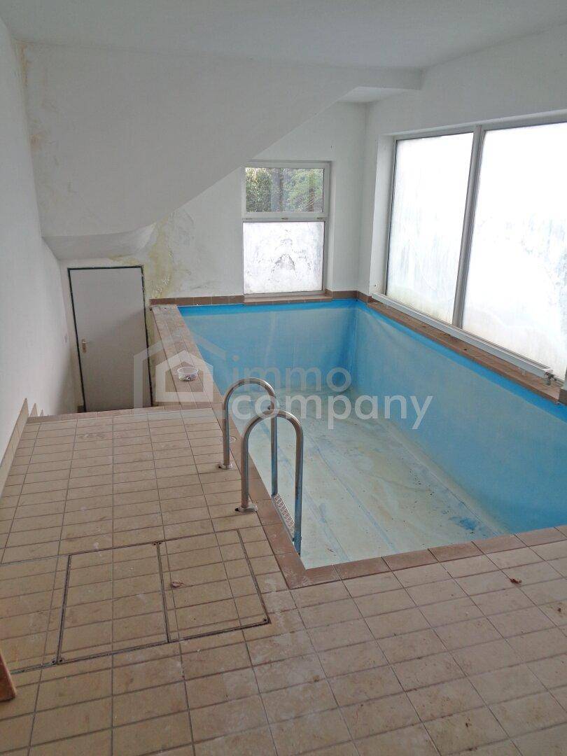 Innenpool in einem Raum mit Fliesenboden und großen Fenstern.