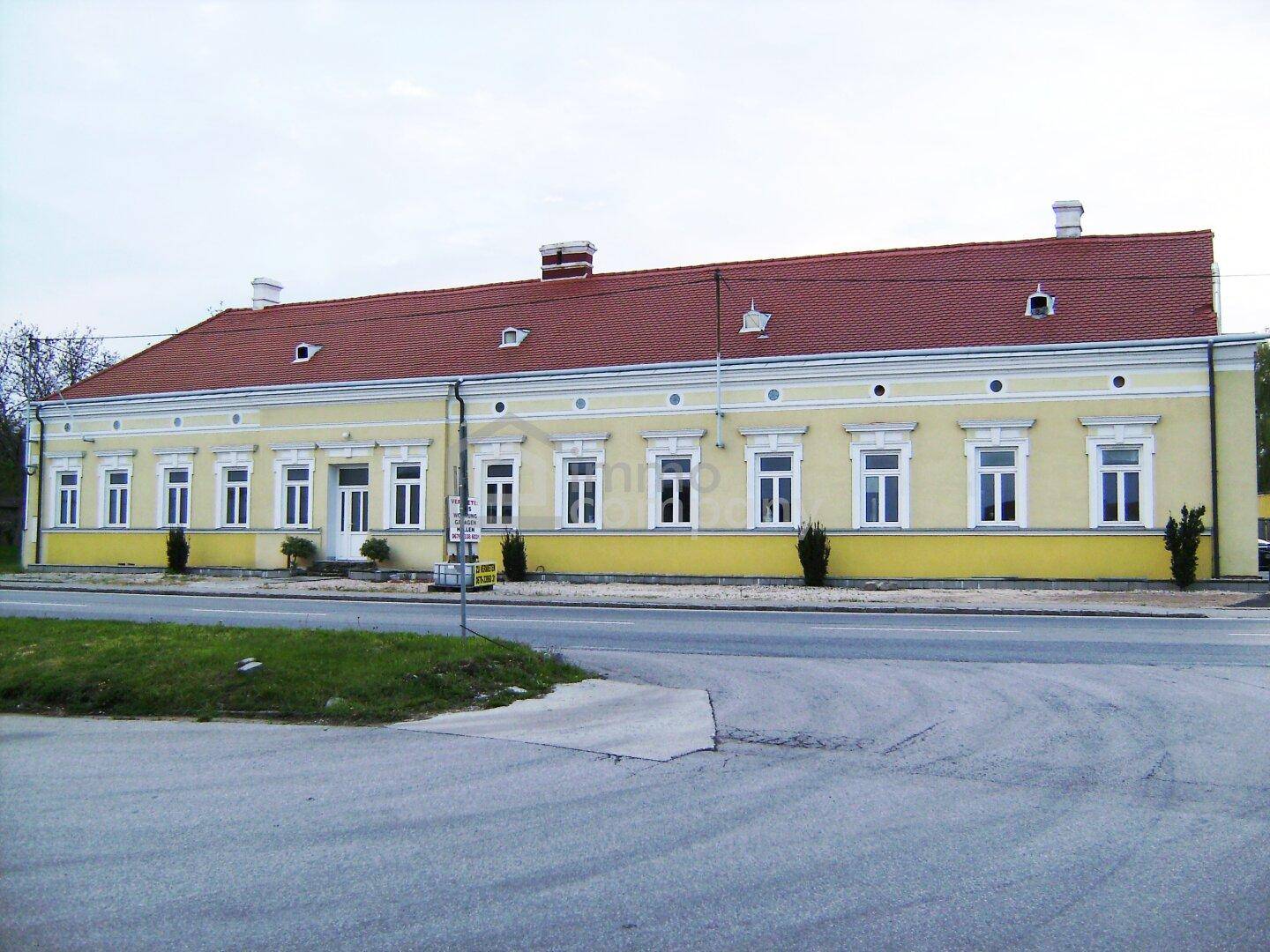 Lange, gelbe Fassade eines historischen Gebäudes mit vielen Fenstern und rotem Ziegeldach.