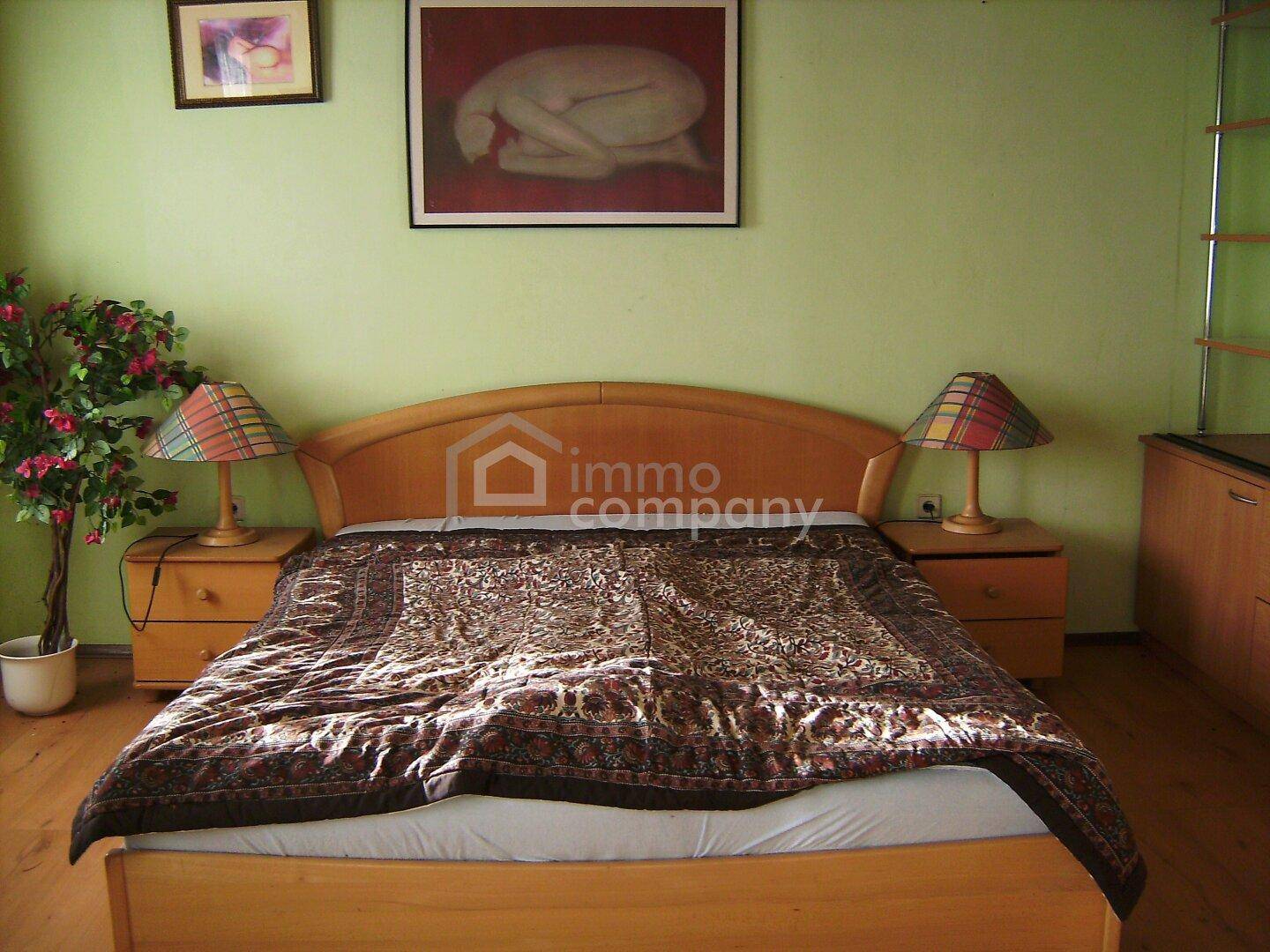 Schlafzimmer mit Doppelbett, Nachttischen und grün gestrichenen Wänden.