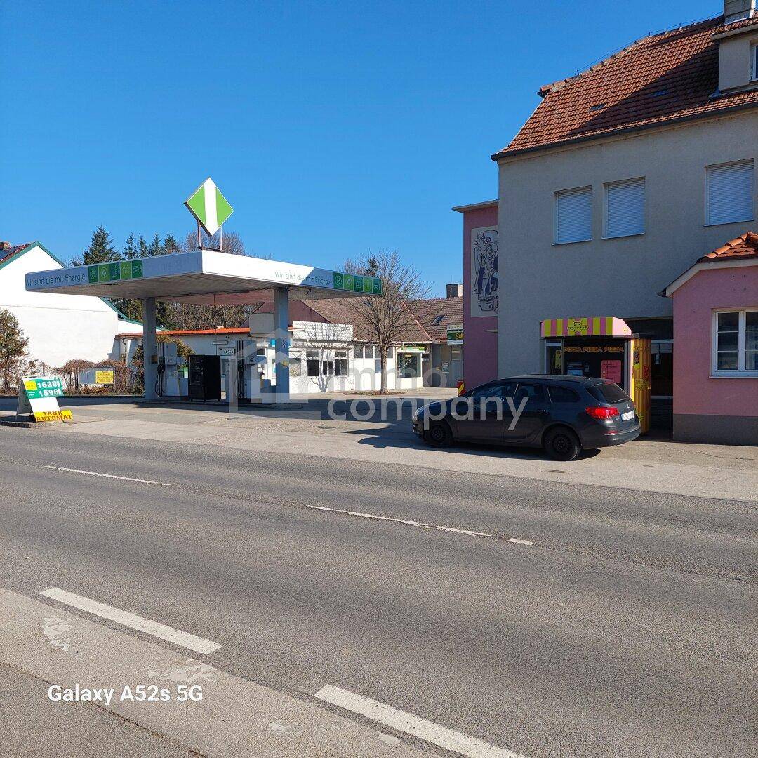 Blick auf eine Tankstelle mit einem angrenzenden Gebäude und einem geparkten Auto an einem sonnigen Tag.