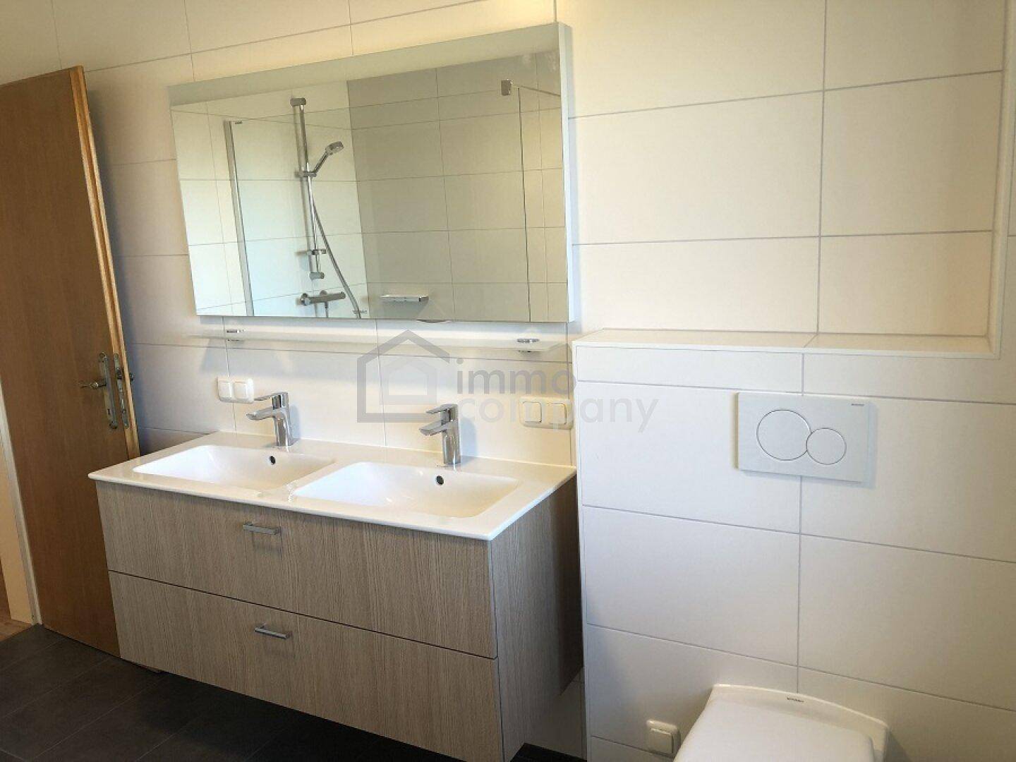 Modernes Badezimmer mit Doppelwaschbecken, großem Spiegel und Wand-WC.