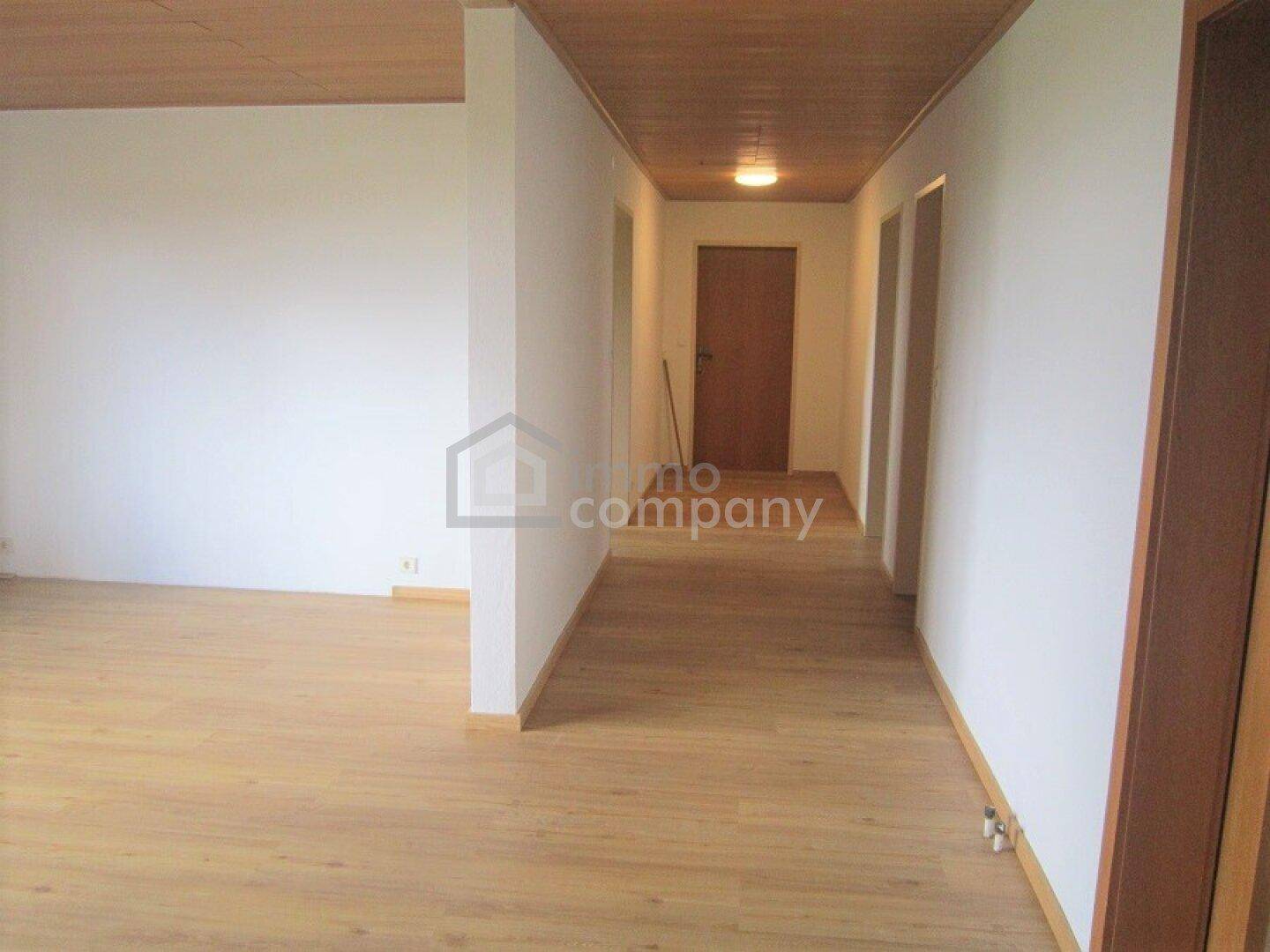 Heller Flur mit Holzboden und Holzdecke, der zu weiteren Räumen führt.