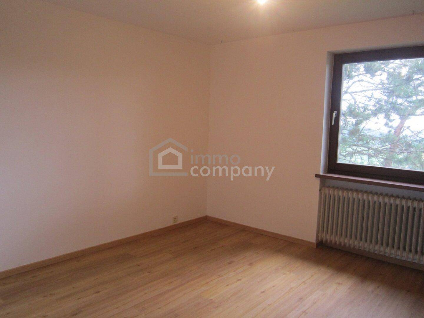 Schlafzimmer mit Holzboden, Fenster und Heizkörper, bereit zur individuellen Gestaltung.