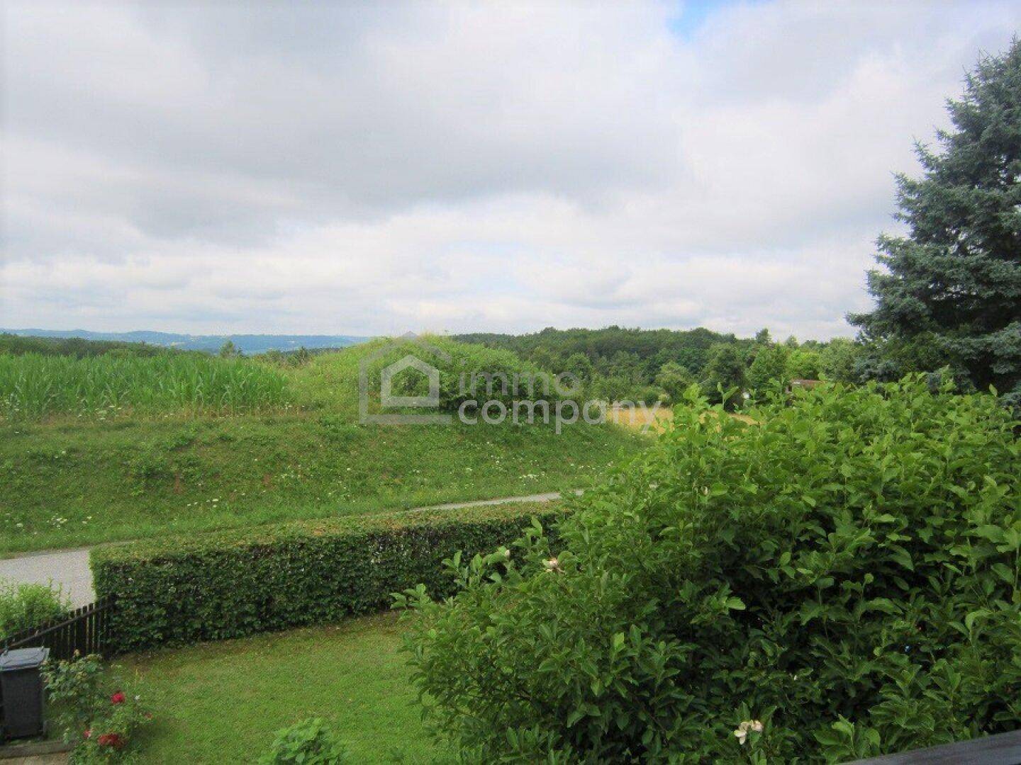 Weitläufiger Gartenbereich mit Hecke und Blick auf die umliegende Landschaft.