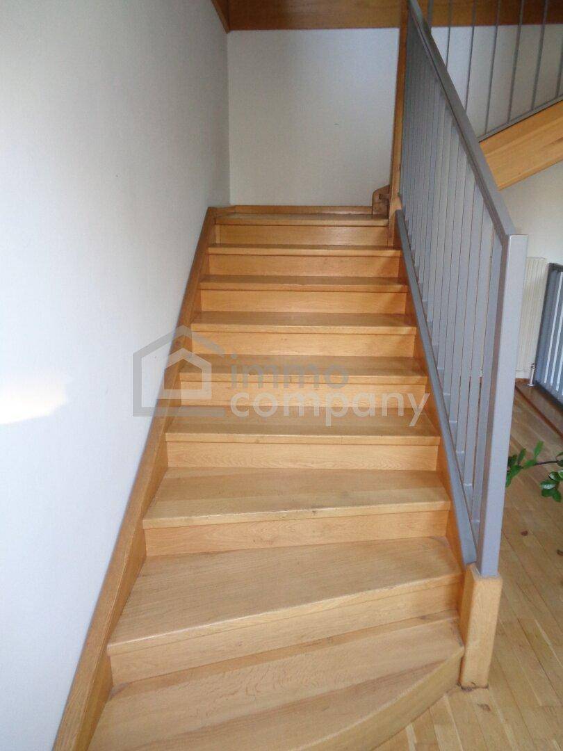 Eine helle Holztreppe mit Metallgeländer, die in die oberen Etagen führt.