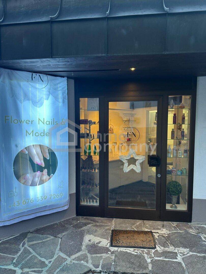 Eingangsbereich eines Geschäfts mit Glastüren, Schaufenster und Werbebanner.