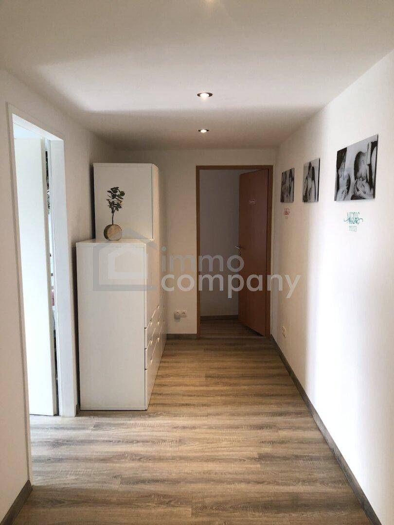 Heller Flur mit Laminatboden, weißen Schränken und Bildern an der Wand.