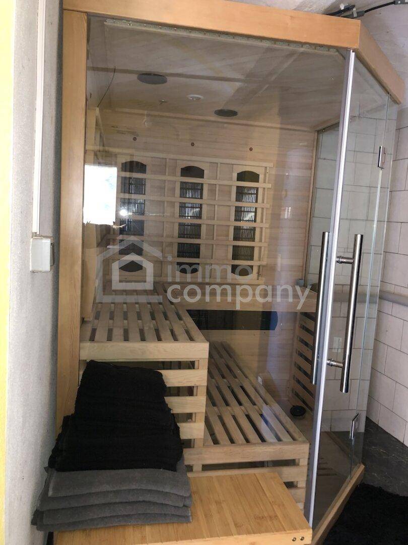 Moderne Sauna mit Holzbänken und Glastür für Entspannung und Wellness.