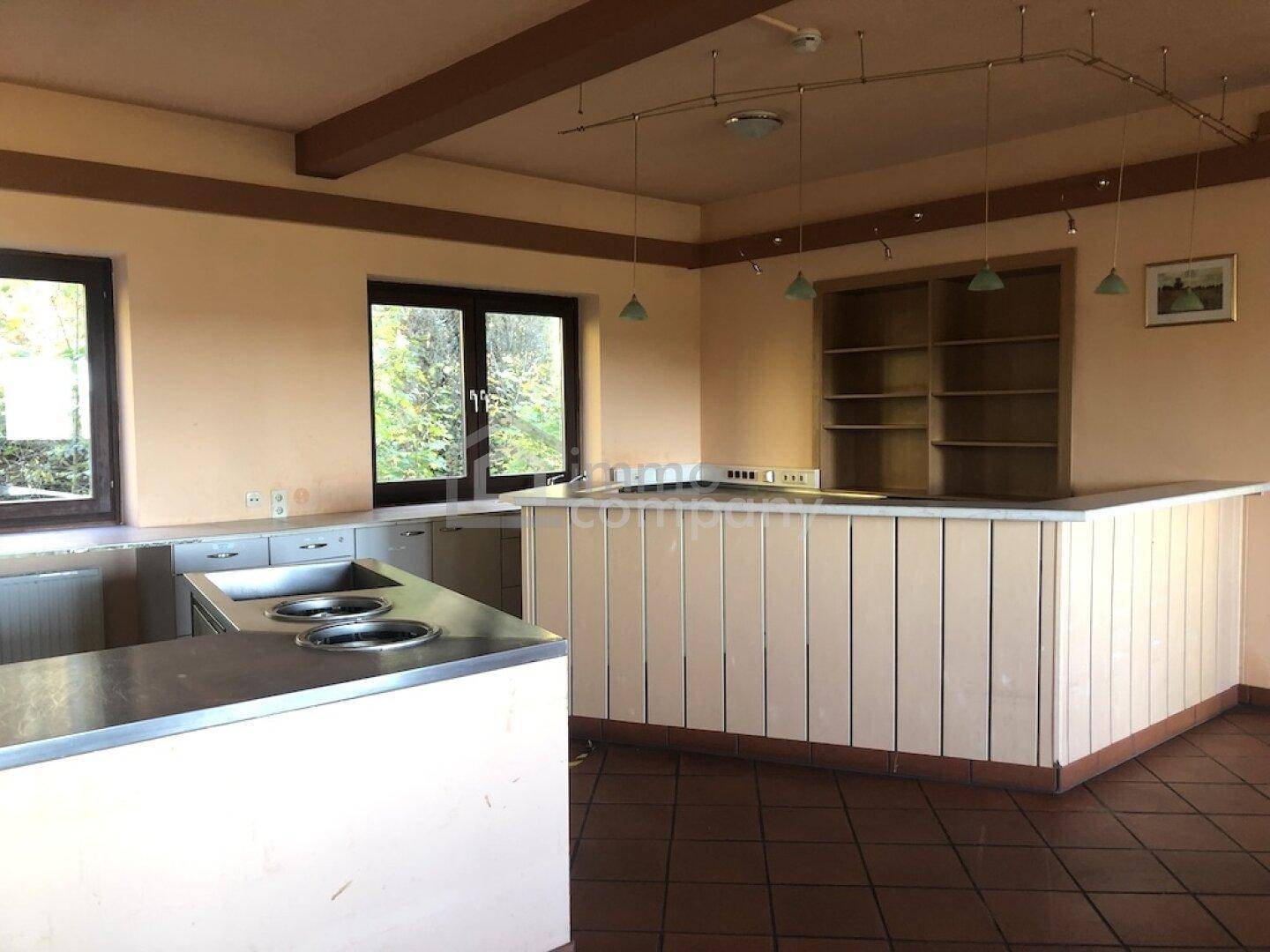Große Küche oder Kantine mit Edelstahlarbeitsflächen, eingebauten Kochfeldern und Holztheke.