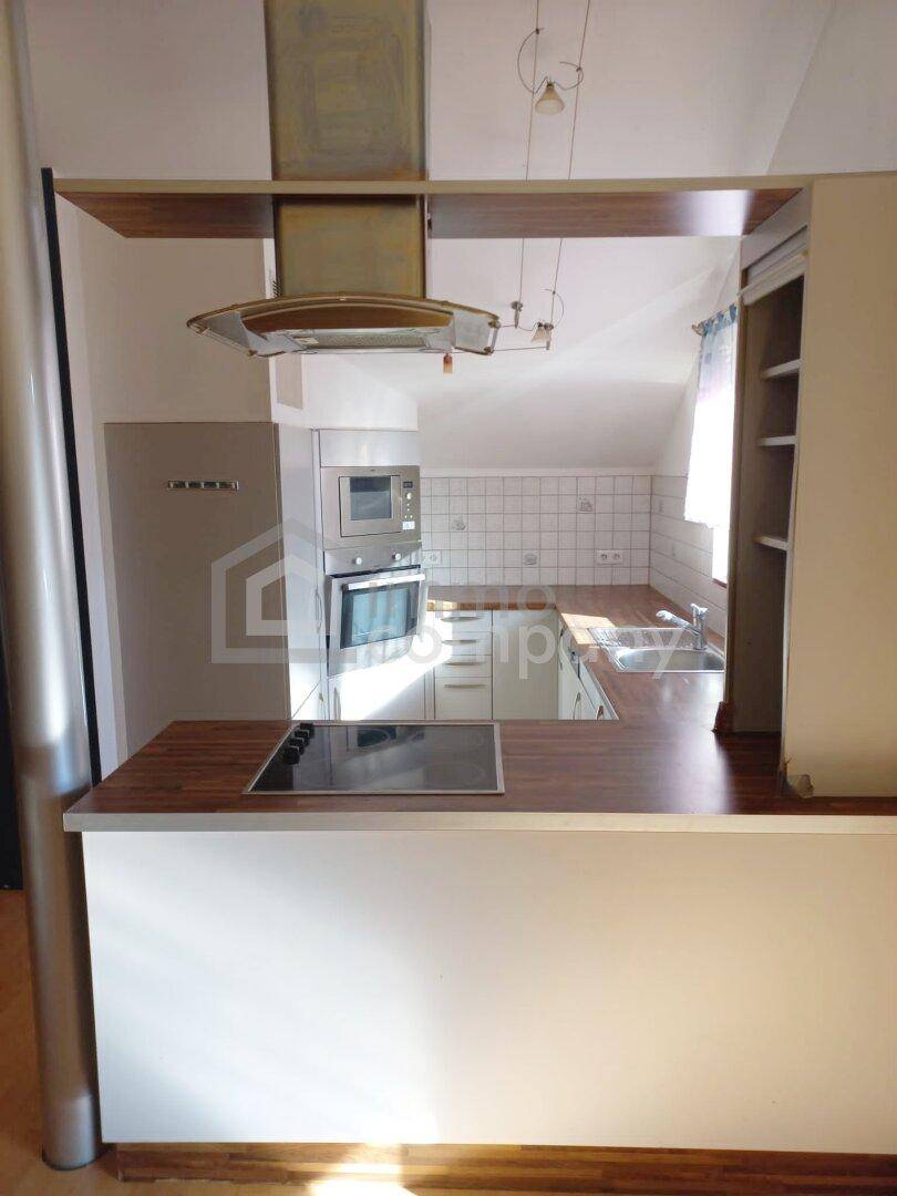 Halboffene Küche mit Frühstücksbar, Einbaugeräten und Fenster für natürliches Licht.