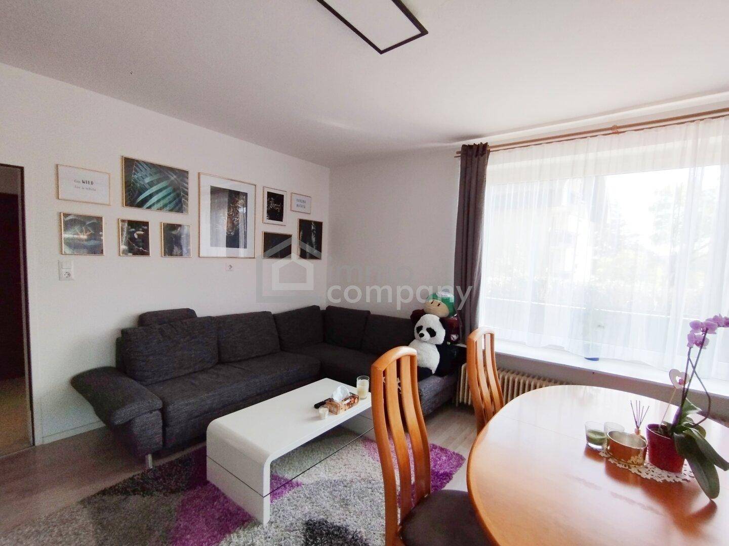 Gemütlicher Wohnbereich mit Ecksofa, Esstisch und Blick ins Grüne durch große Fenster.