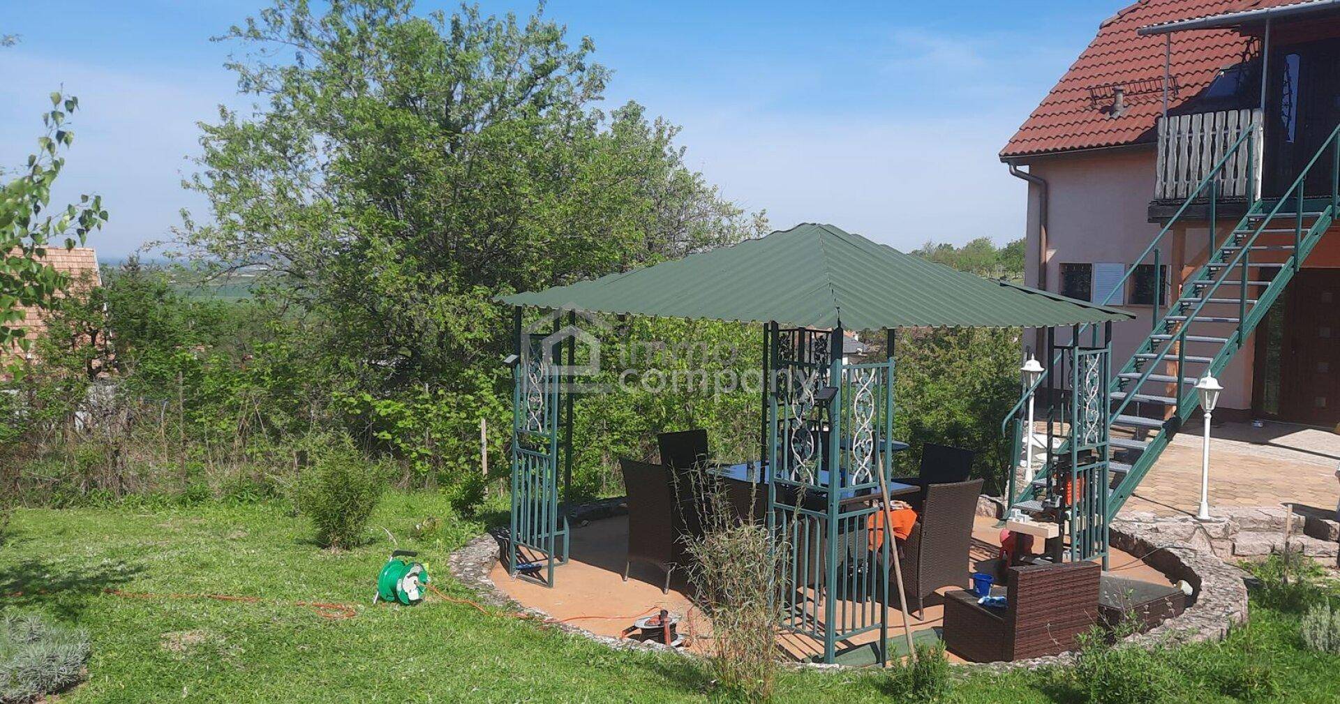 Gepflegter Garten mit einem grünen Pavillon und Sitzgelegenheiten für entspannte Stunden im Freien.
