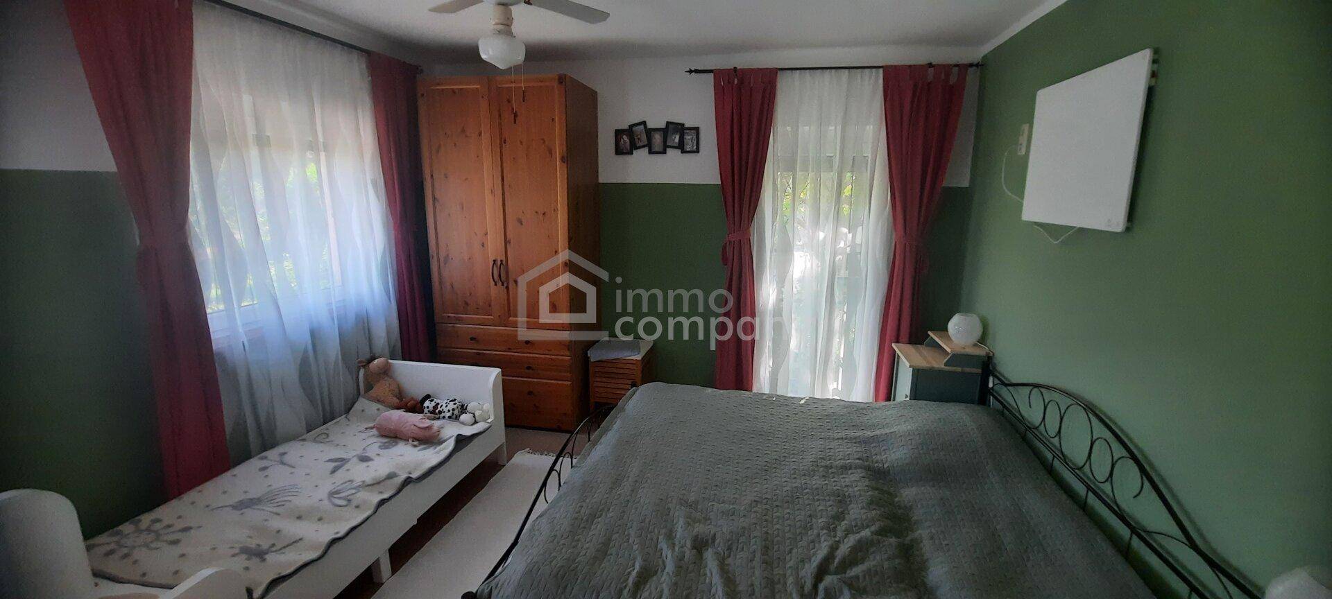 Gemütliches Schlafzimmer mit grün gestrichenen Wänden, Holzschrank und zwei Betten.