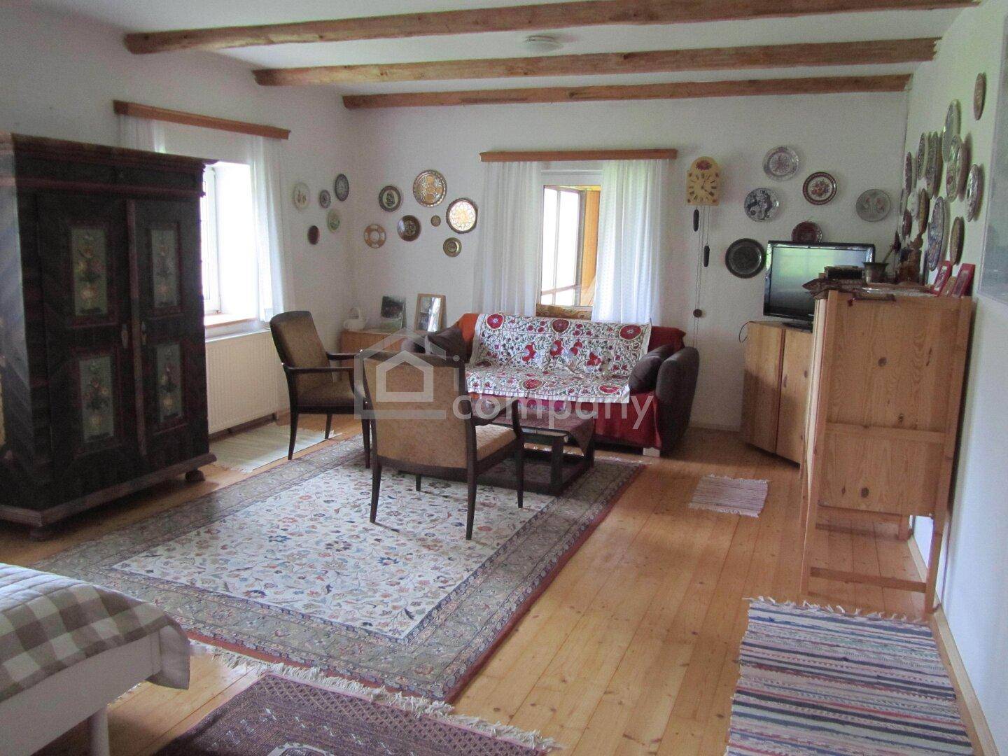 Rustikales Wohnzimmer mit sichtbaren Holzbalken, Holzboden und traditioneller Einrichtung, hell und geräumig.