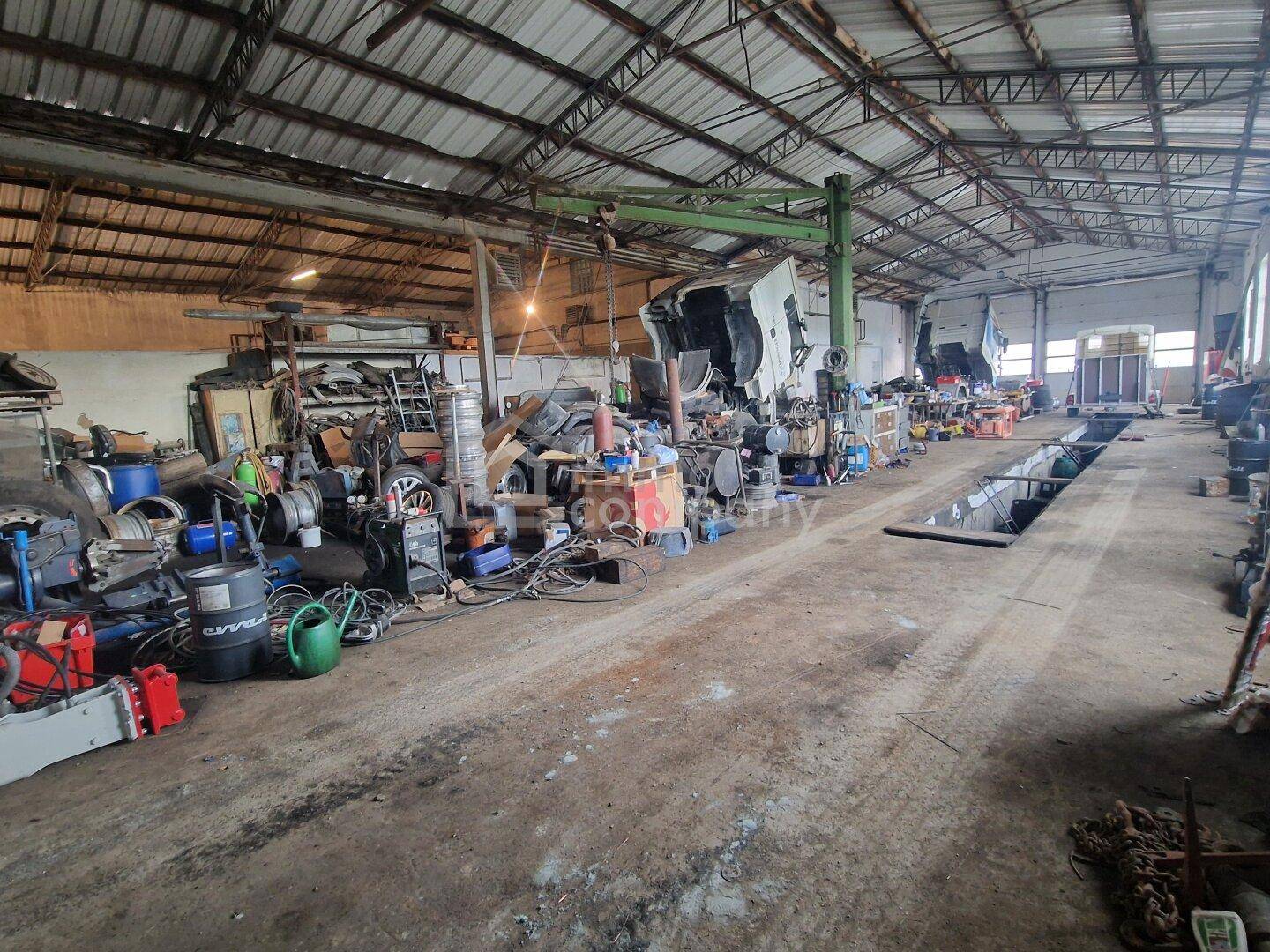 Große Werkstatthalle mit hoher Decke, sichtbaren Metallträgern und vielen Werkzeugen und Geräten.