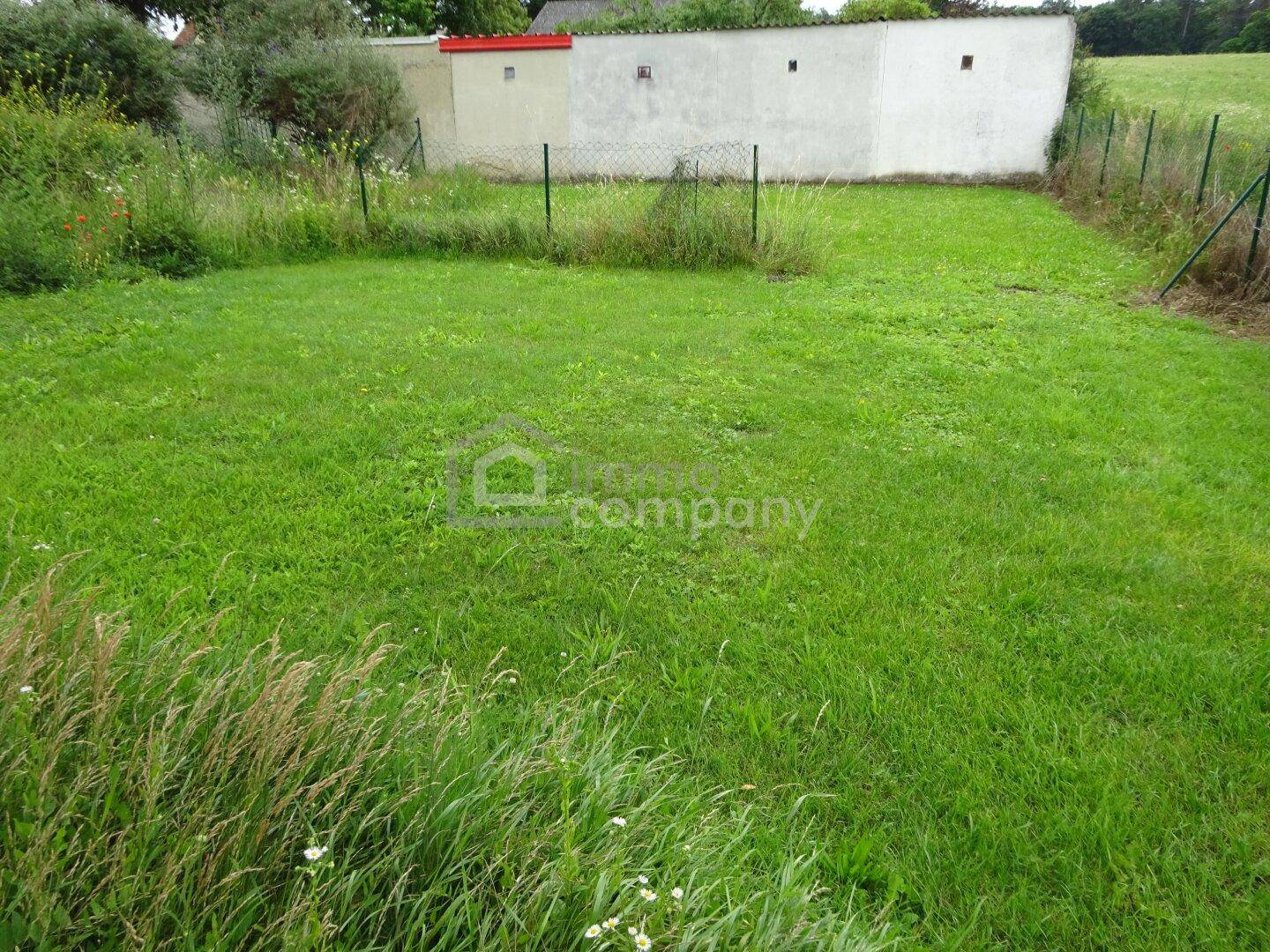 Grüner Gartenbereich mit Rasenfläche und Zaun, bietet Platz für Erholung im Freien.