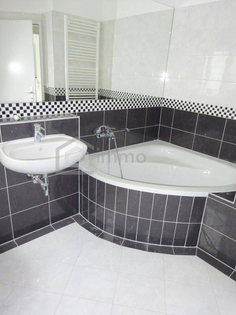 Badezimmer mit Eckbadewanne, Waschbecken und beheiztem Handtuchhalter in modernem Design.