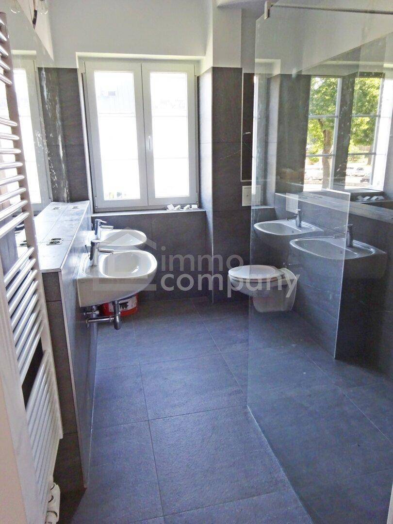 Modernes Badezimmer mit Doppelwaschbecken, Dusche und einem Fenster, das einen Blick auf die umliegende Natur bietet.