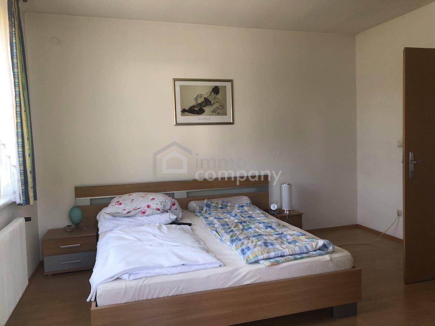 Schlafzimmer mit Doppelbett, Holzboden und hellen Wänden, bietet eine ruhige Atmosphäre.