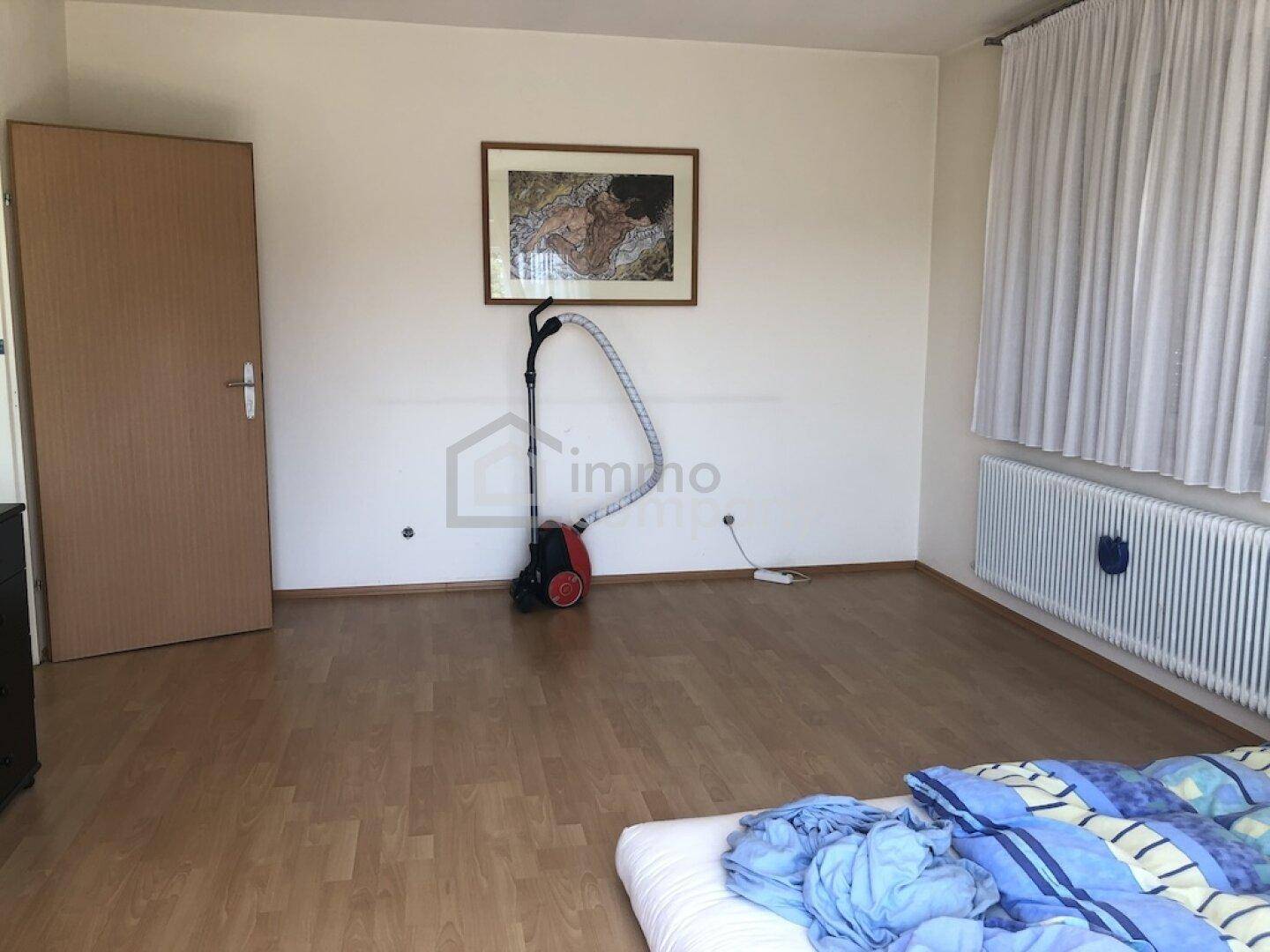 Helles Schlafzimmer mit Laminatboden und einem Heizkörper unter dem Fenster, bereit zur Einrichtung.