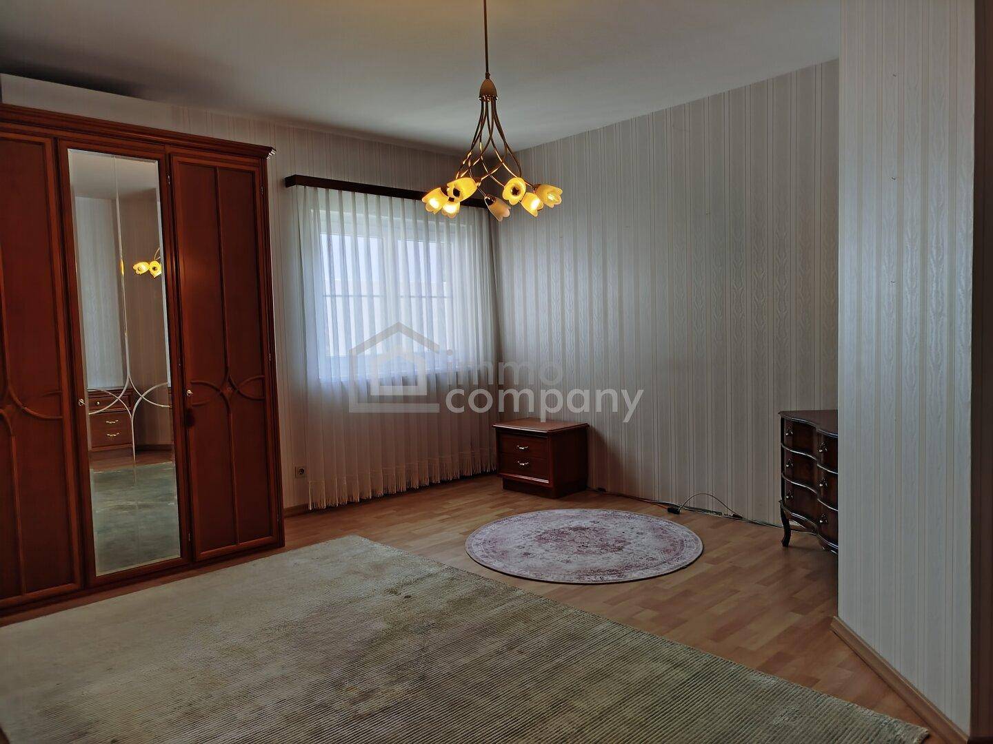 Gemütliches Schlafzimmer mit großem Kleiderschrank, Laminatboden und einem Fenster für natürliches Licht.