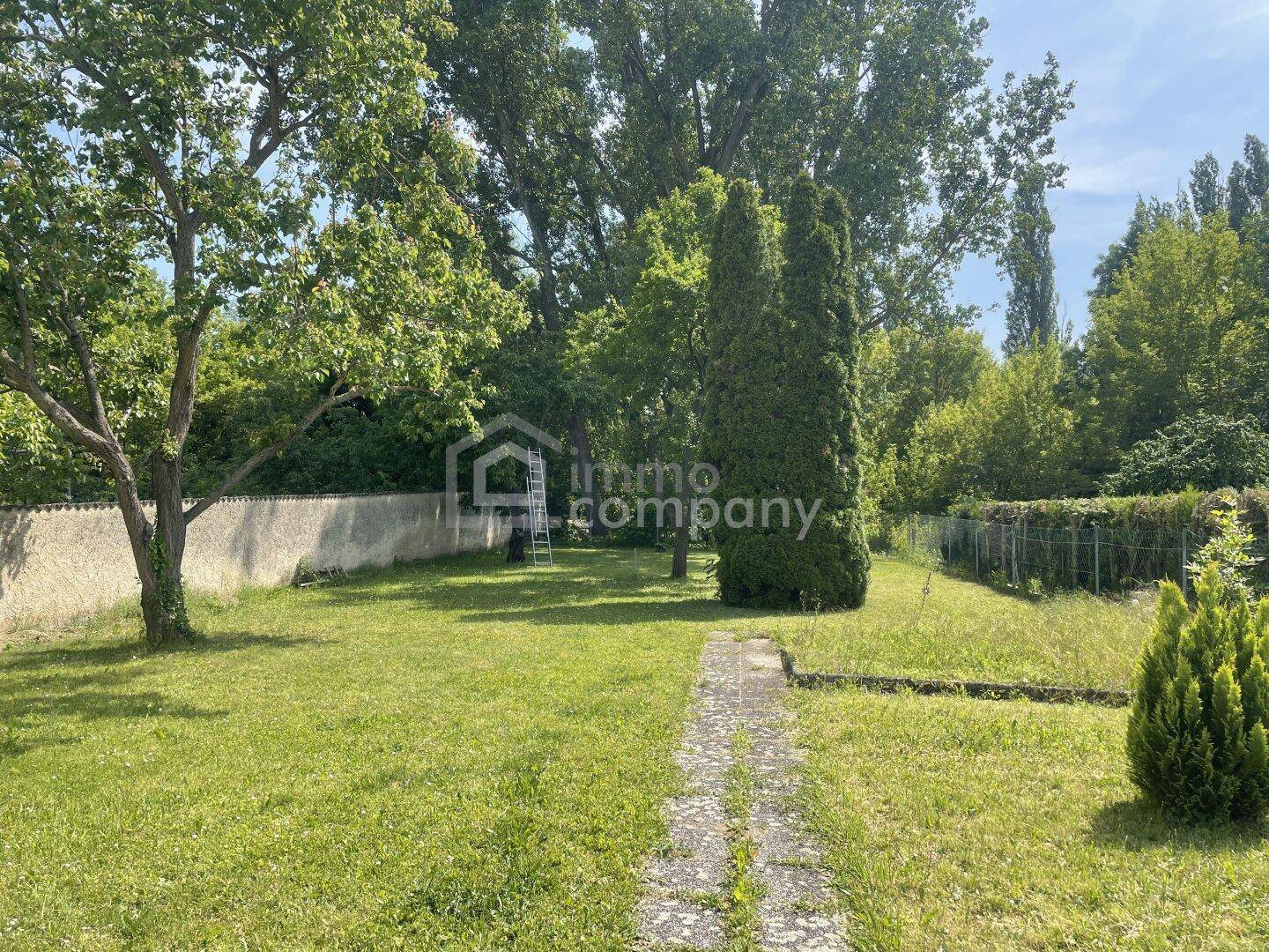 Großer Garten mit Rasenfläche, altem Baumbestand und einem Steinweg.